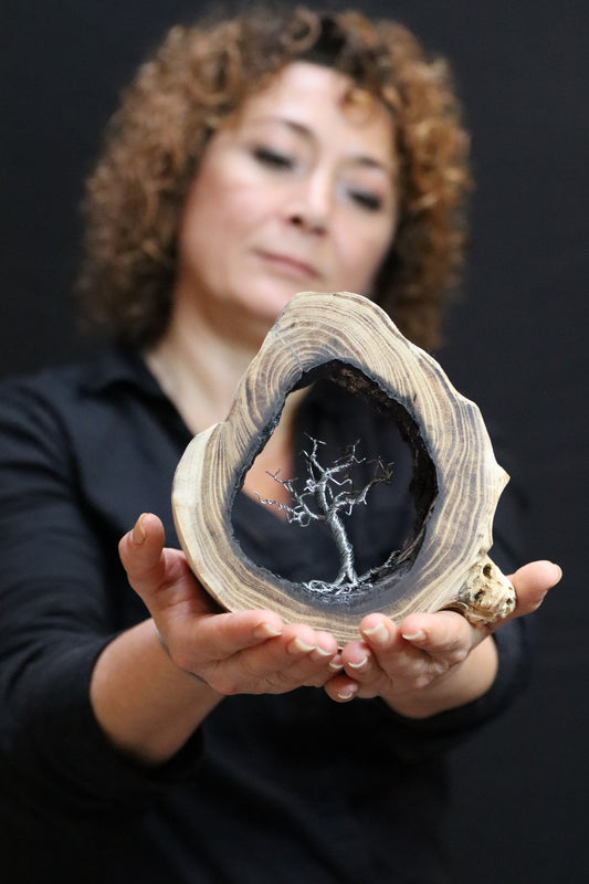Vrouw houdt een uniek houten kunstwerk met een boomsculptuur binnenin voor unieke houten kunstwerken kopen