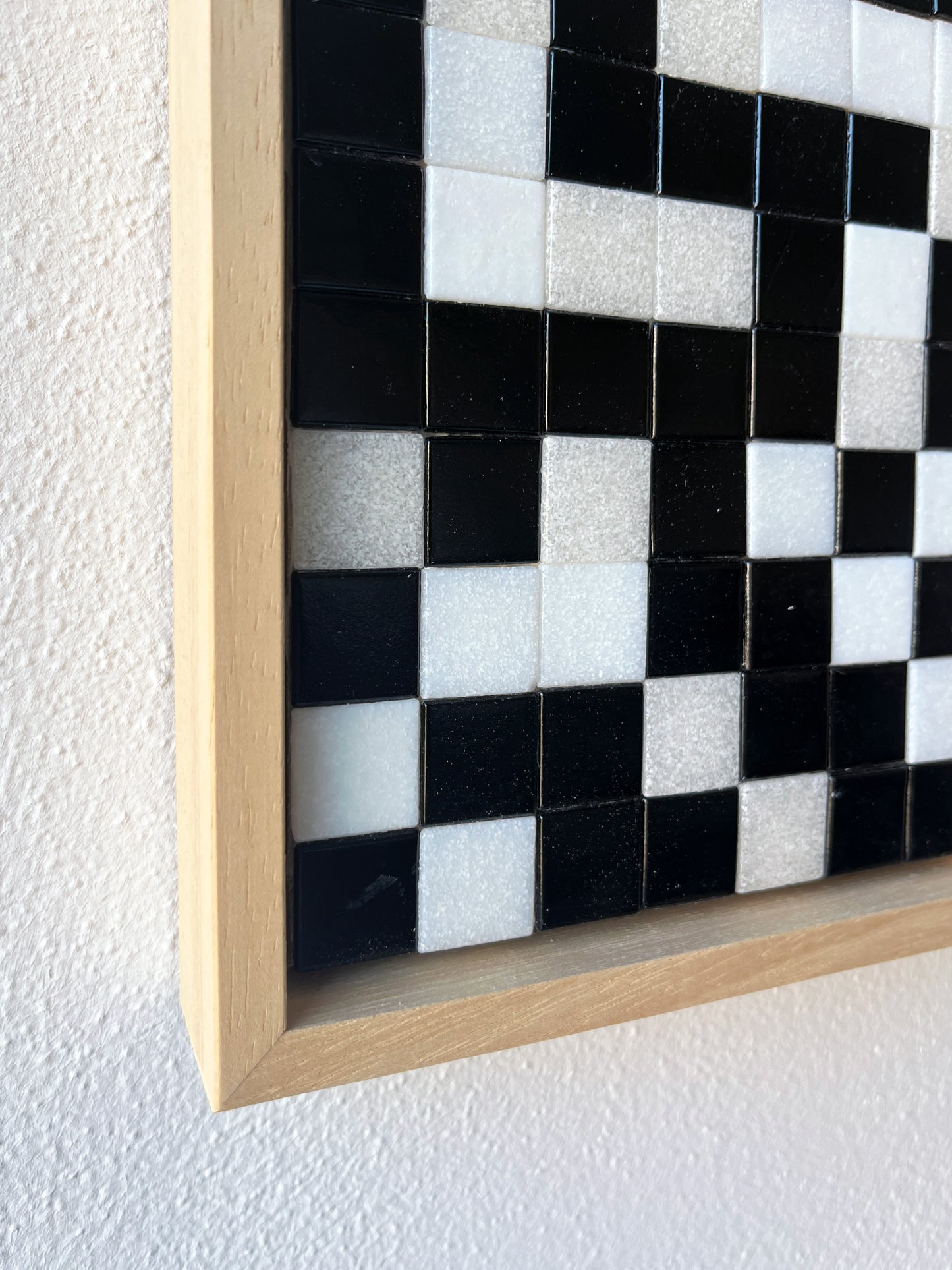 Detail van een modern mozaïek kunstwerk met zwart witte tegels en houten lijst van Guido de Boer