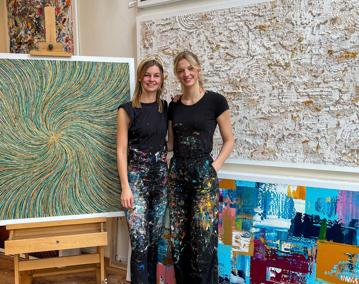 Twee kunstenaars in een studio met moderne schilderijen van Atelier58 aan de muur en op een ezel