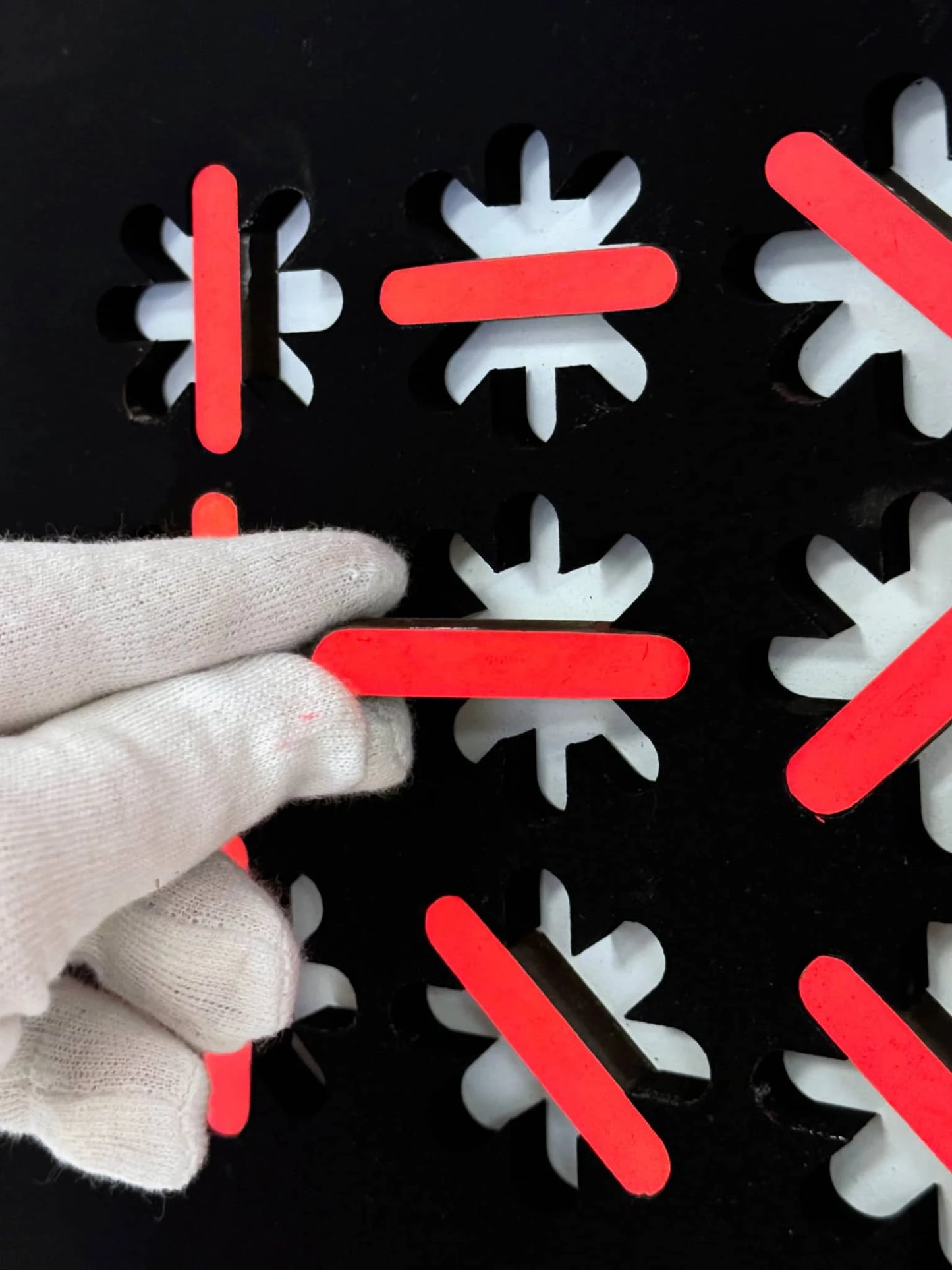 Hand die een scherp abstract kunstobject aanraakt met zwarte en rode elementen