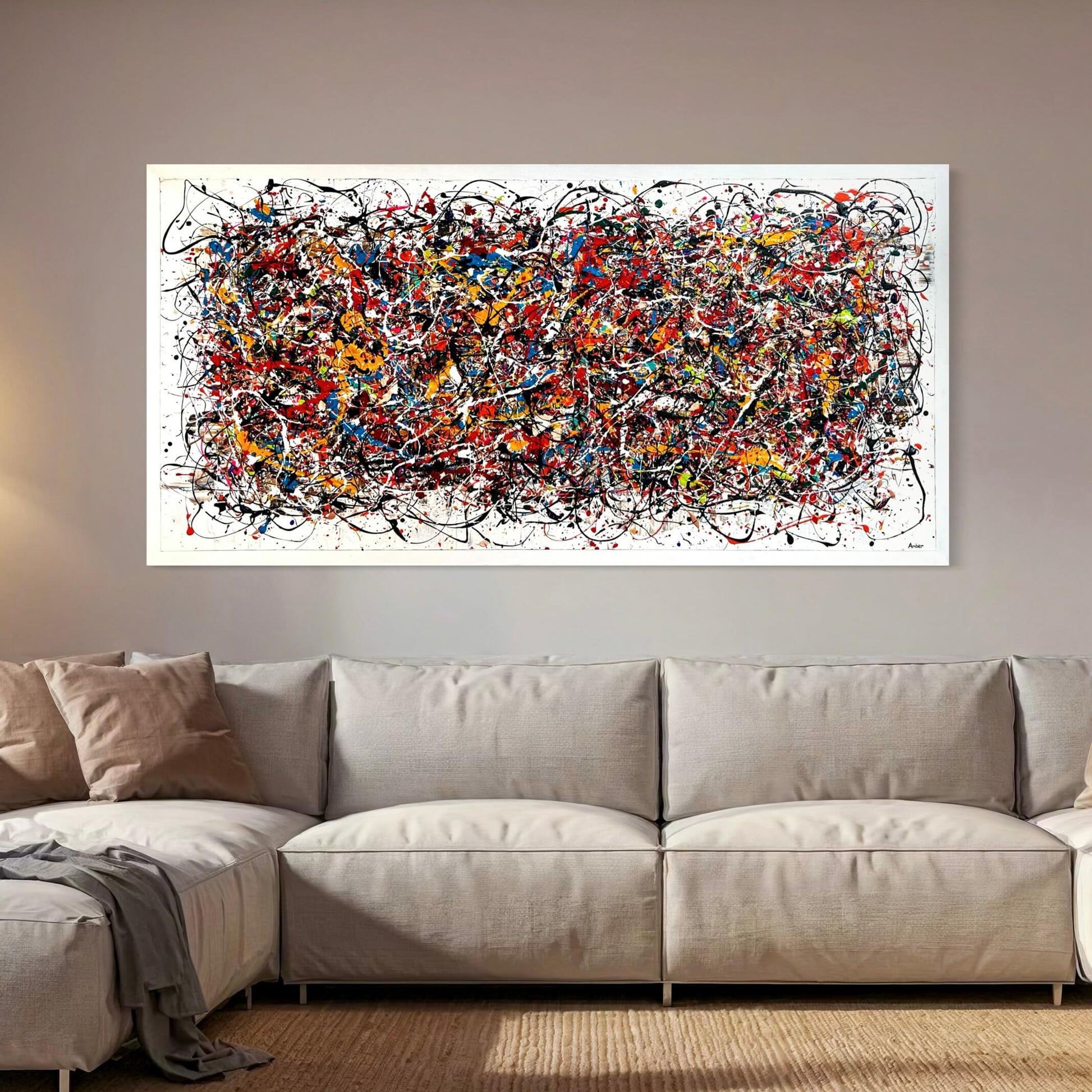 Langwerpig kunstwerk van Atelier58 met kleurrijke abstracte verfspatten boven een beige bank
