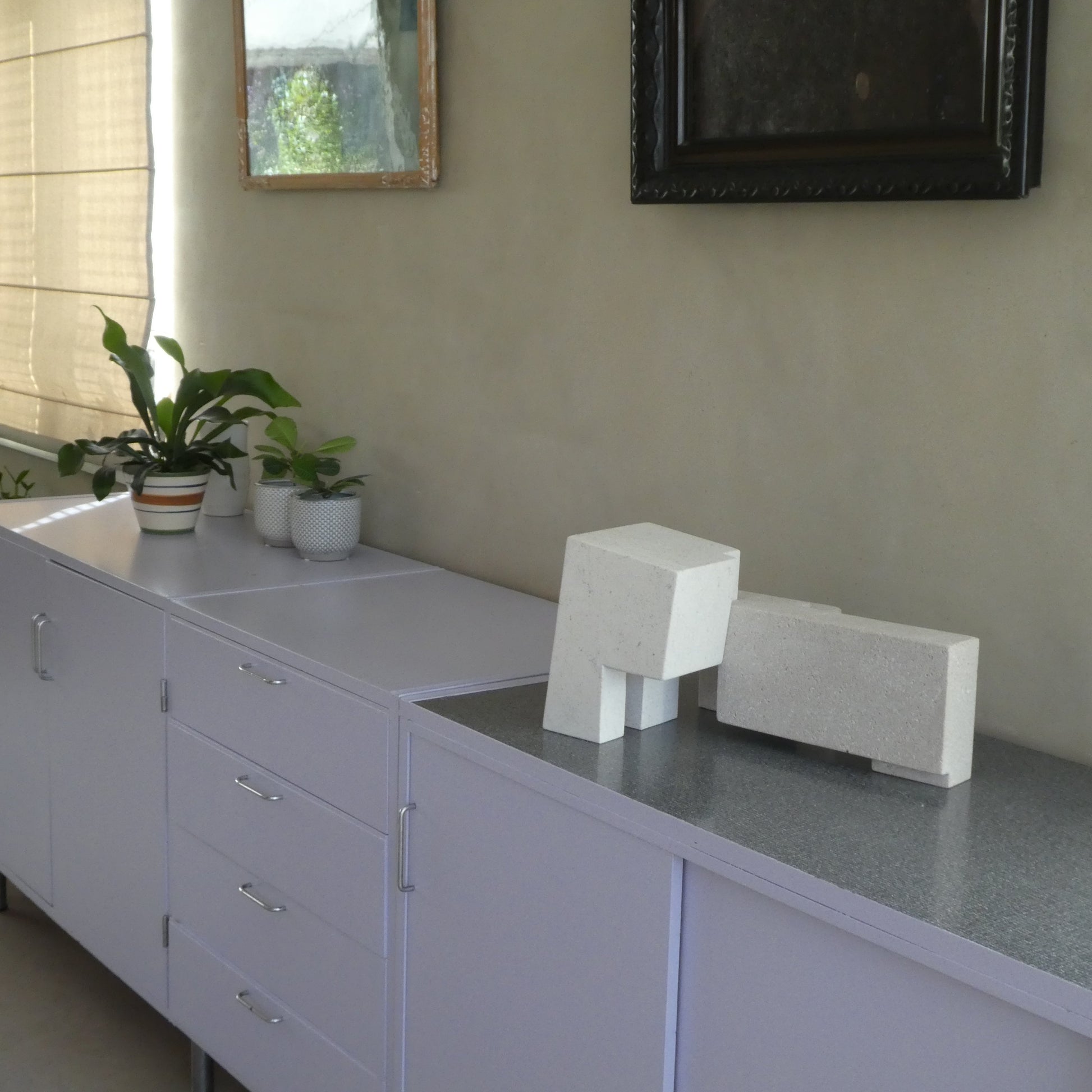 Moderne woonkamer met abstracte sculptuur op een kast en planten in het decor