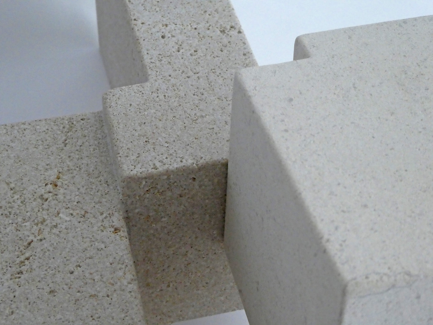 Abstracte sculptuur van lichte steen met geometrische vormen en textuur.