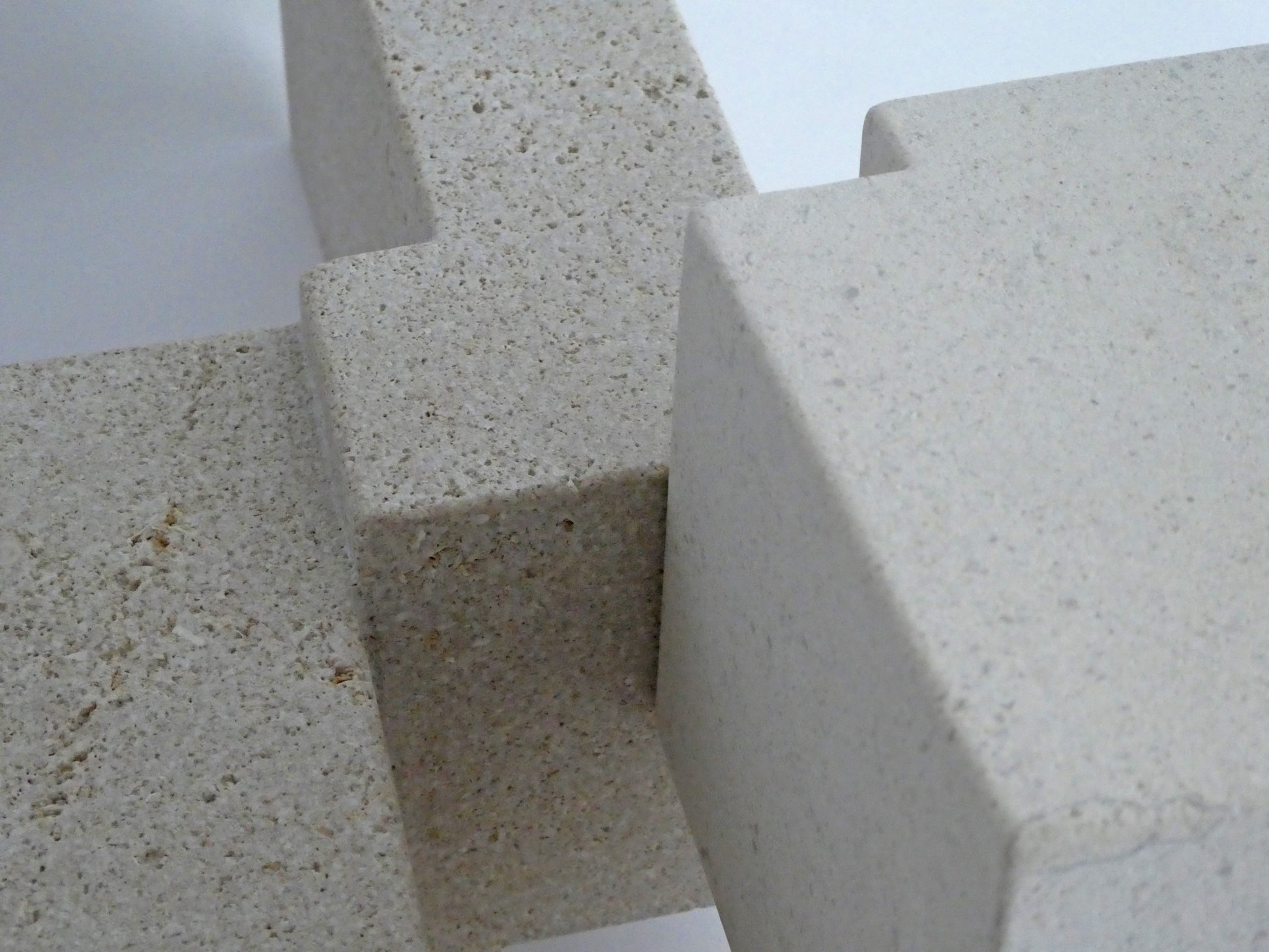 Abstracte sculptuur van lichte steen met geometrische vormen en textuur.