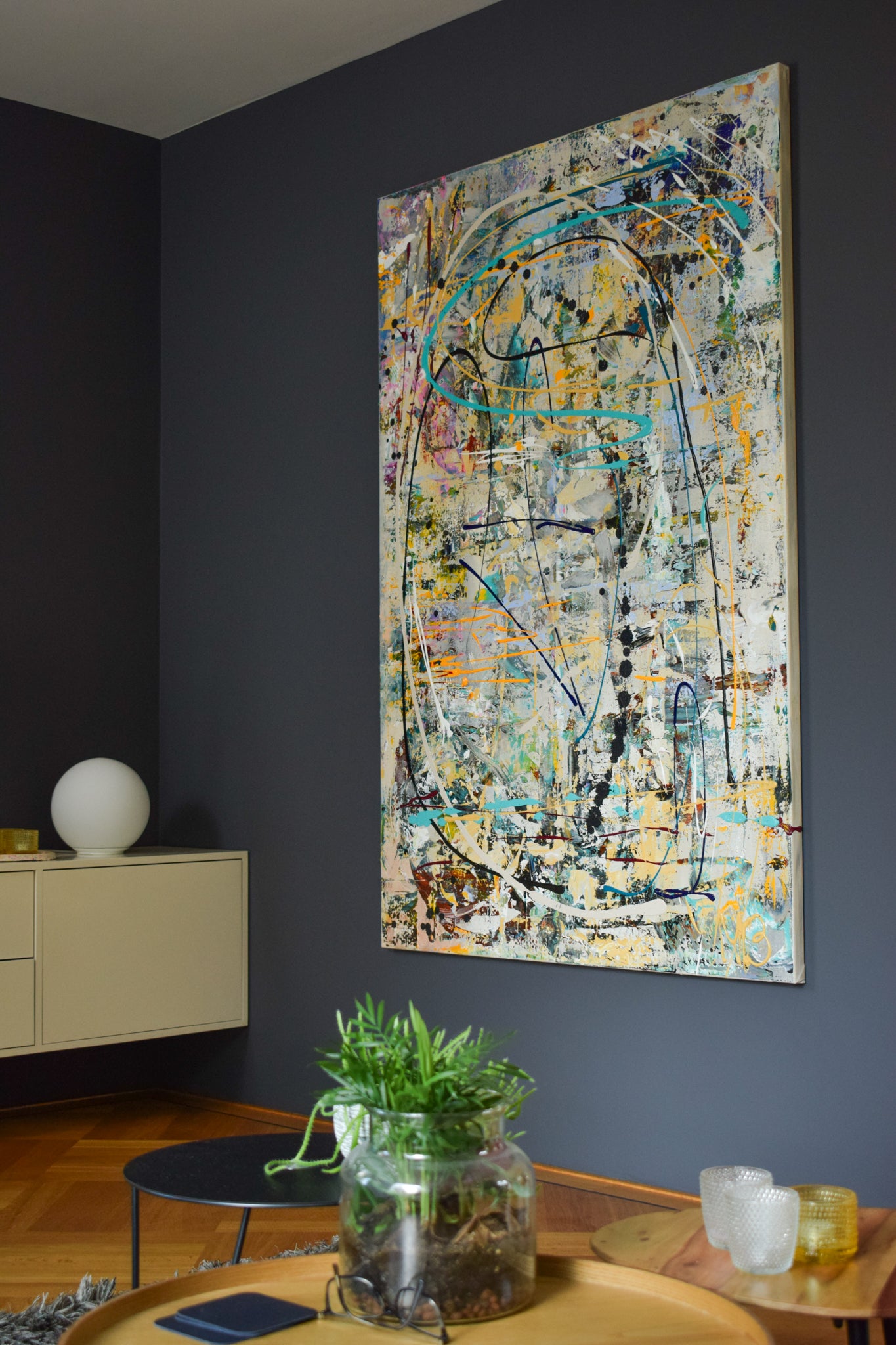 Schilderijen van Art by Marieke Brouwers groot abstract doek hangend aan donkere muur in moderne woonkamer