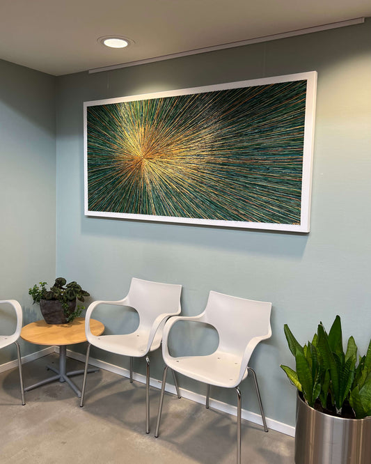 Langwerpig schilderij met abstract ontwerp in groene en gouden tinten gehangen boven witte stoelen in moderne wachtruimte