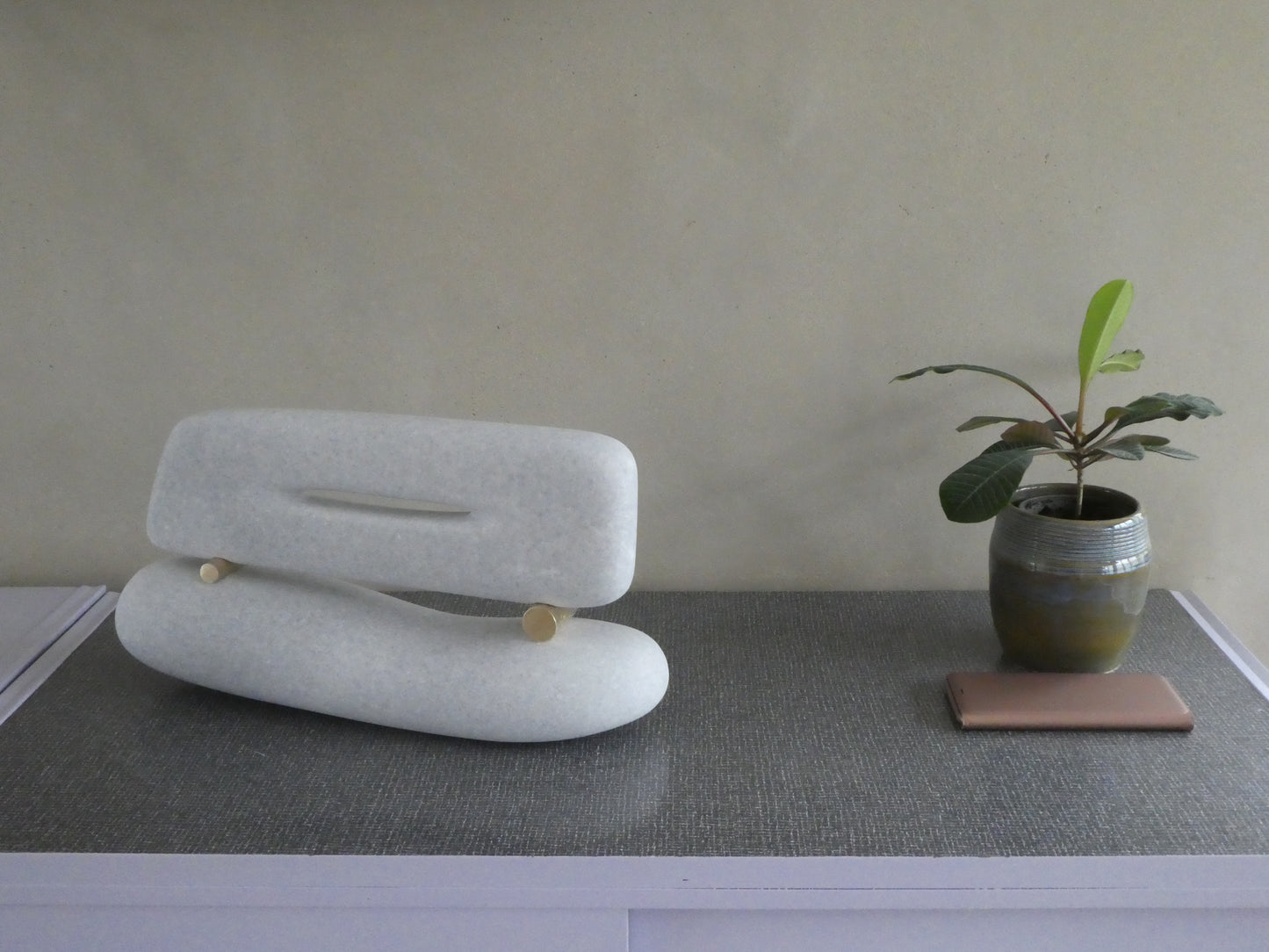 Minimalistische marmer sculptuur van Fieke de Roij op een tafel met een plantenpot