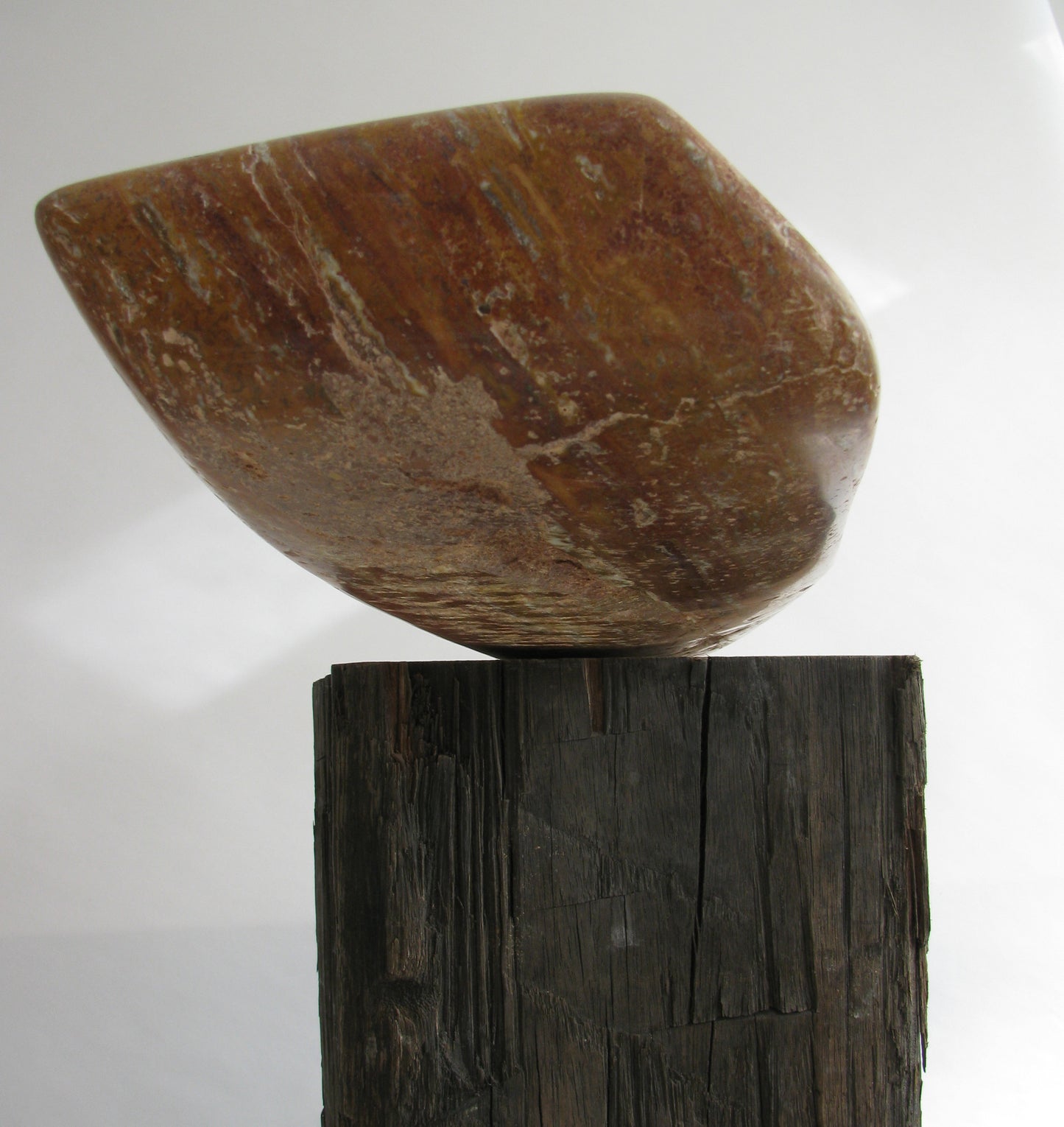 Travertijn sculptuur van Fieke de Roij op een houten sokkel met unieke vormen