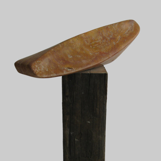 Travertijn sculptuur op een houten sokkel met een unieke, organische vorm en warme kleuren