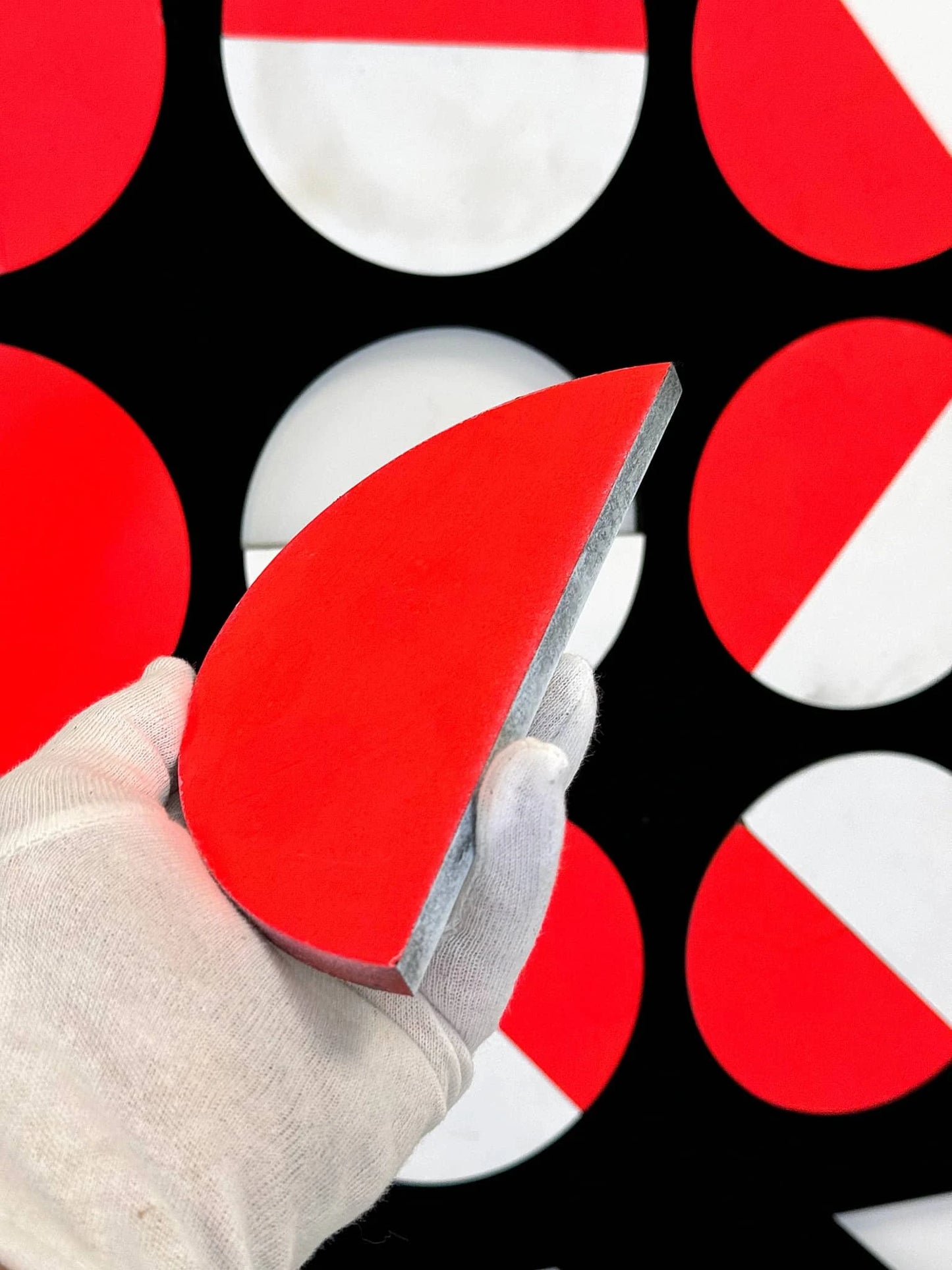 Kunstwerk in rood en wit met een hand die een half cirkelvormig stuk vasthoudt, wandkunstwerk van Rob Stolte